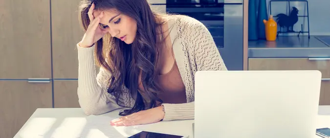 Woman doing paperwork with a laptop and digital tablet.