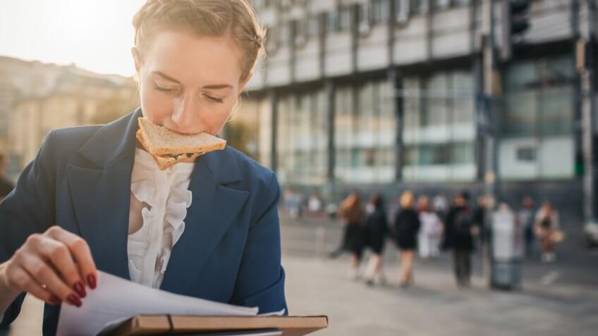 Busy woman is in a hurry, she does not have time, she is going to eat snack on the go.