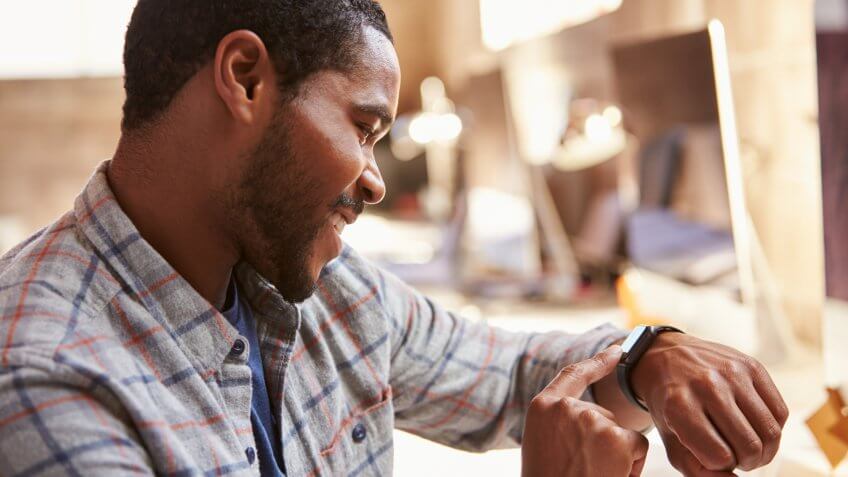 Businessman Looking At Smart Watch In Design Office.