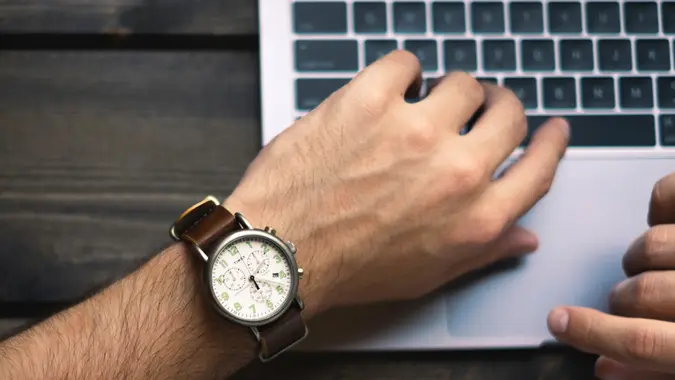 Person wearing wrist watch using laptop