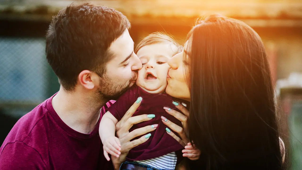 parents kissing infant on the cheeks