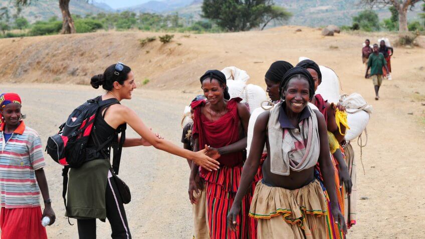 "Konso, Ethiopia - August 9, 2010: An Israeli woman traveling in Ethiopia greets local villagers with a culturally correct handshake, in which one's left hand rest on the inside of the elbow during the handshake.