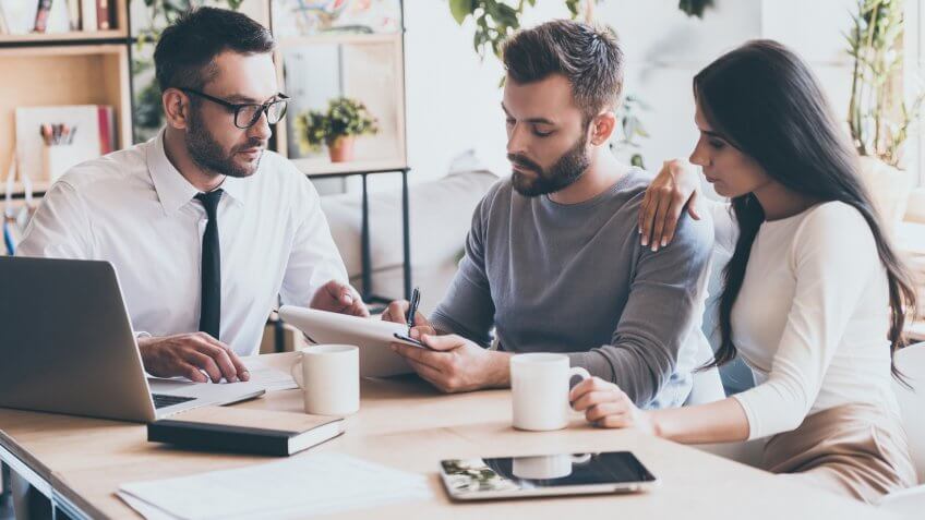 Couple signing document with advisor