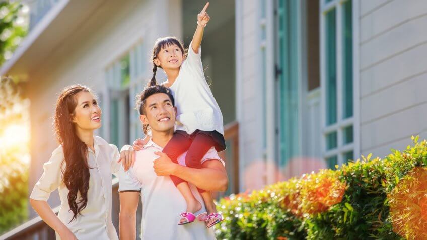 Beautiful family portrait smiling outside their new house with sunset.