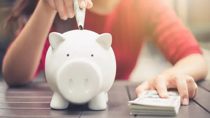 woman hand putting money bank note dollar into piggy for saving money wealth and financial concept.