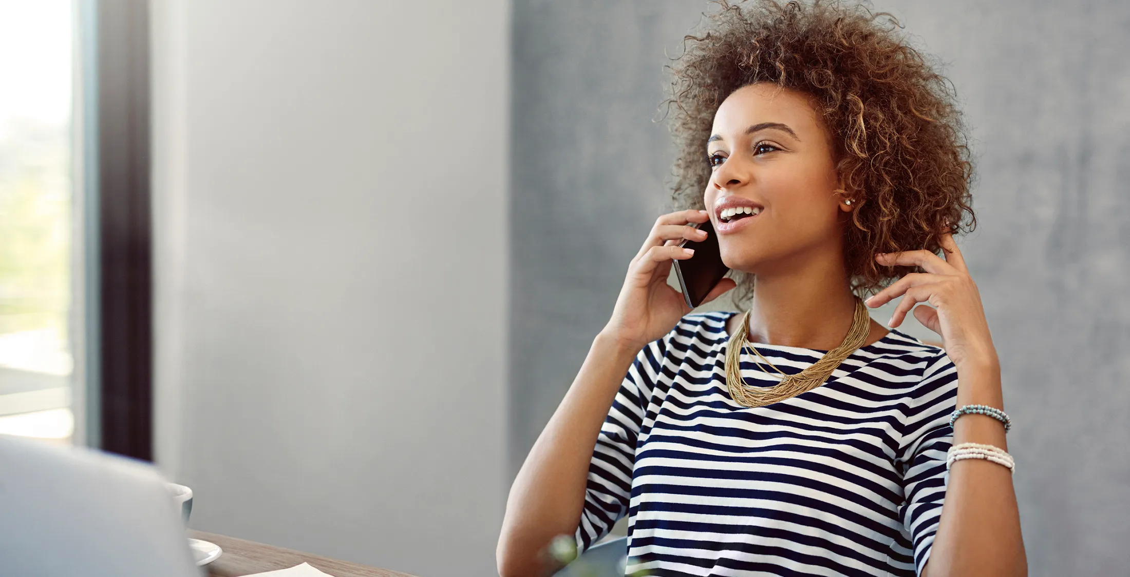 young woman talk on the phone while sitting at a desk at home