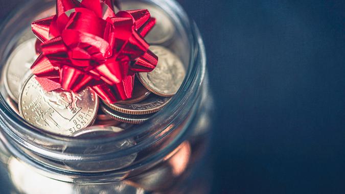 Christmas money jar with American currency and topped with bow.