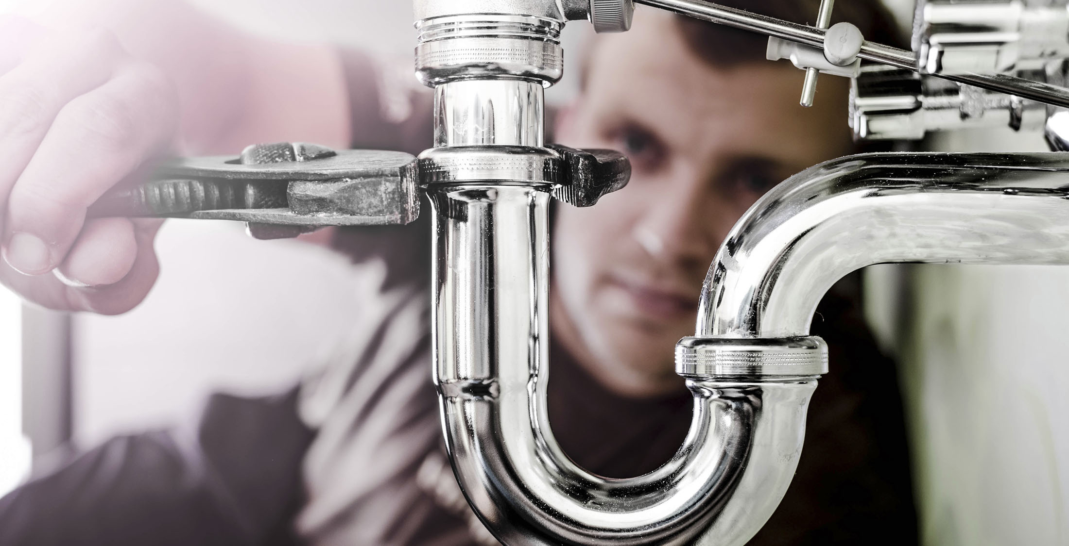 You don't realize how handy you are. Plumber using a wrench to tighten a siphon under a sink
