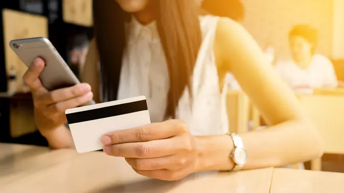 woman on phone and reading credit card