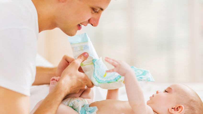 Young father is about to change his baby boy's diapers.