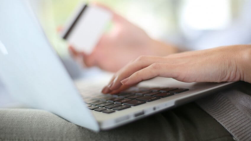 closeup of woman's hands as she types in credit card info