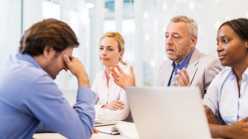 Mature businessman with his colleagues explaining their potential colleague why he didn't get a job.