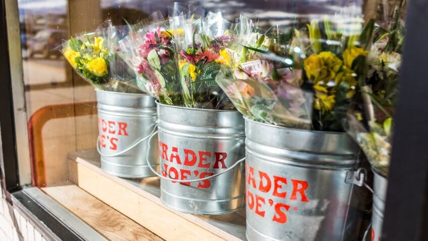 Fairfax, USA - January 18, 2017: Buckets of flowers with Trader Joe's signs viewed from outside of store.