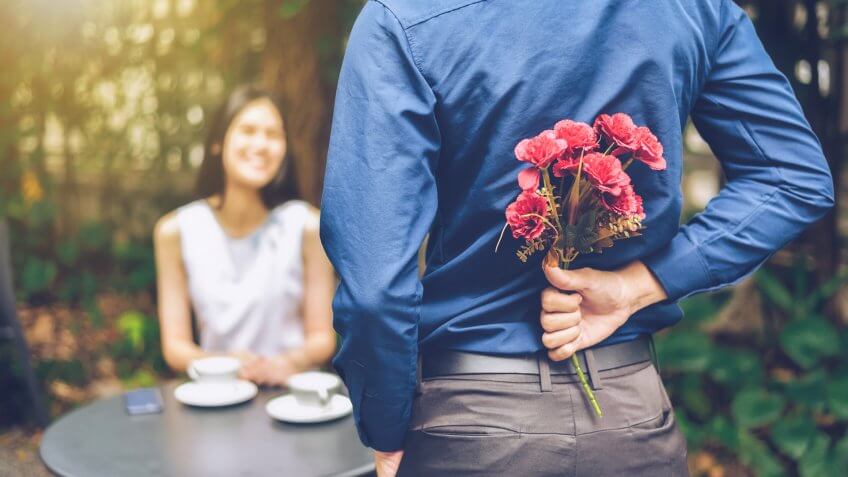 man holding flowers behind his back