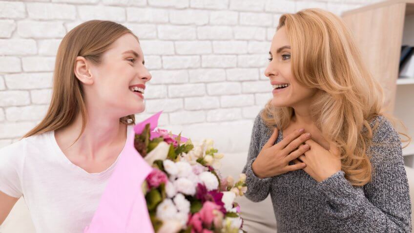 woman giving another woman a bouquet of flowers