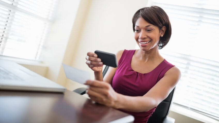 woman happily depositing her check using her mobile smartphone