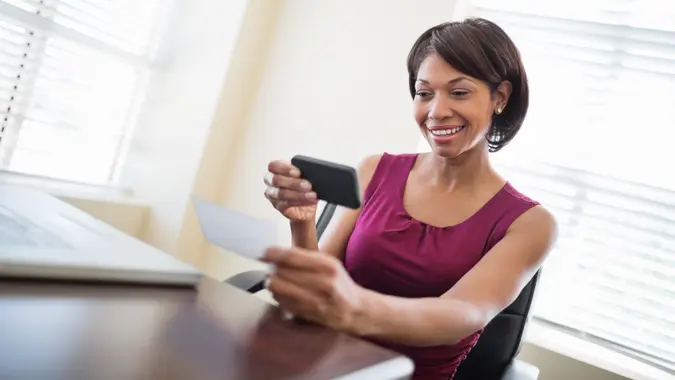 woman happily depositing her check using her mobile smartphone
