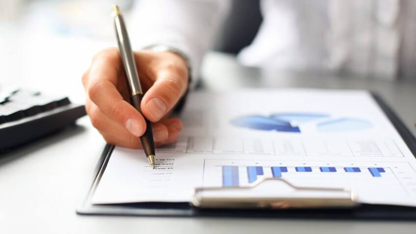 Man writing on a document of charts with his pen
