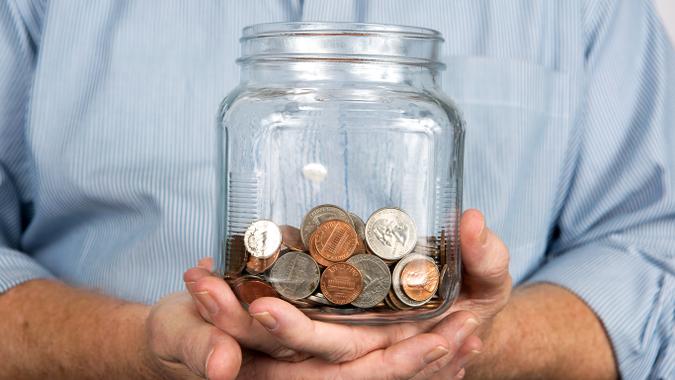 man holding a jar of change