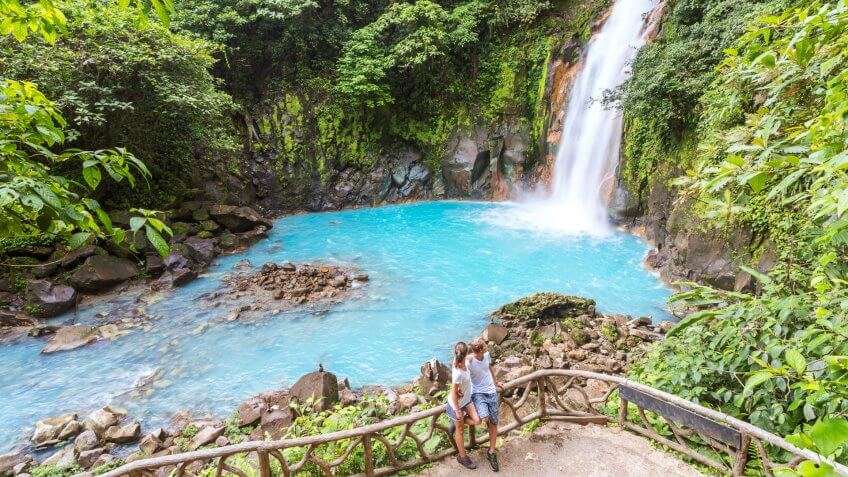 Tourist couple looking at Rio Celeste waterfall, Tenorio Volcano National Park, Guanacaste, Costa Rica.