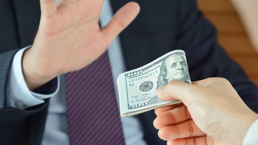 Close up of man refusing stack of hundred dollar bills