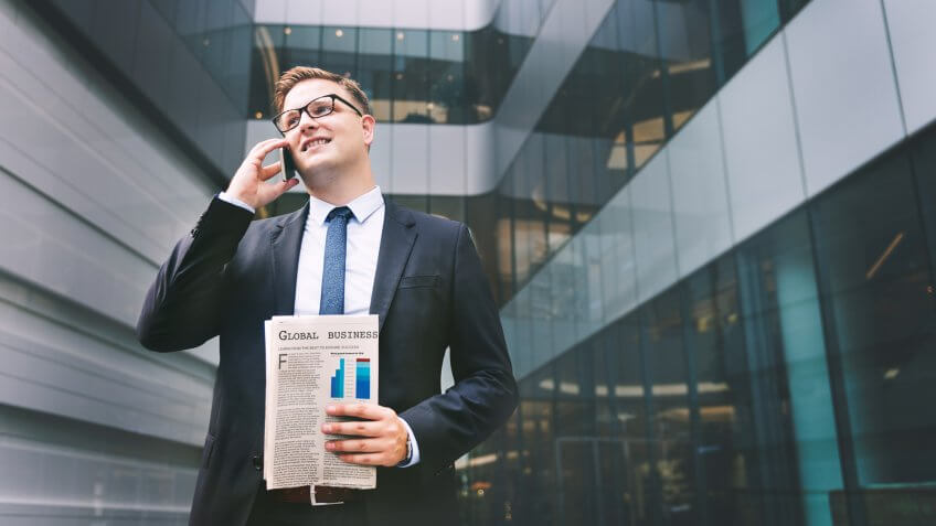 Businessman with newspaper talking on phone