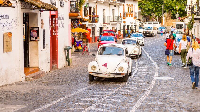 2016: White Taxi car on the street of Taxco, How Much to Tip When Traveling to These 25 Countries, MEXICO - OCT 28, Mexico. The town is known because of its Silver products, TAXCO