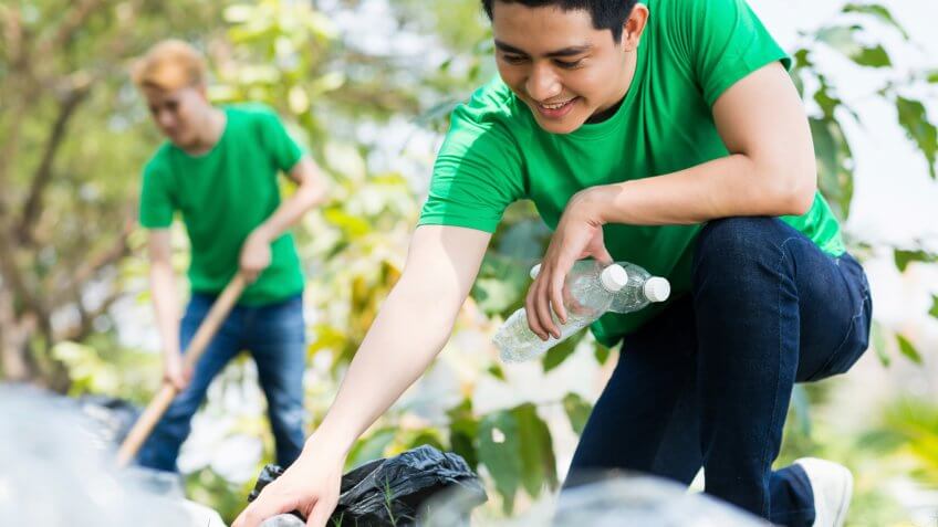 Young man picking up bottles outdoors