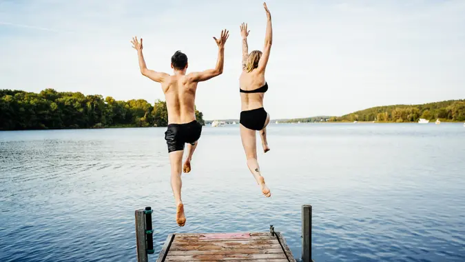 Happy couple jumping into the water from a jetty.