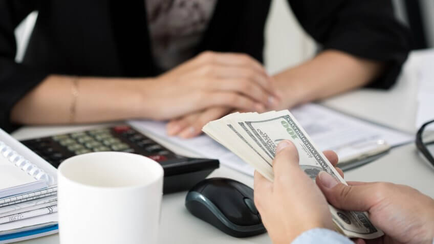 Close up of man offering hundred dollar bills