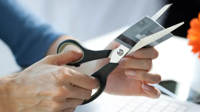 Female hands cutting a credit card with scissors.