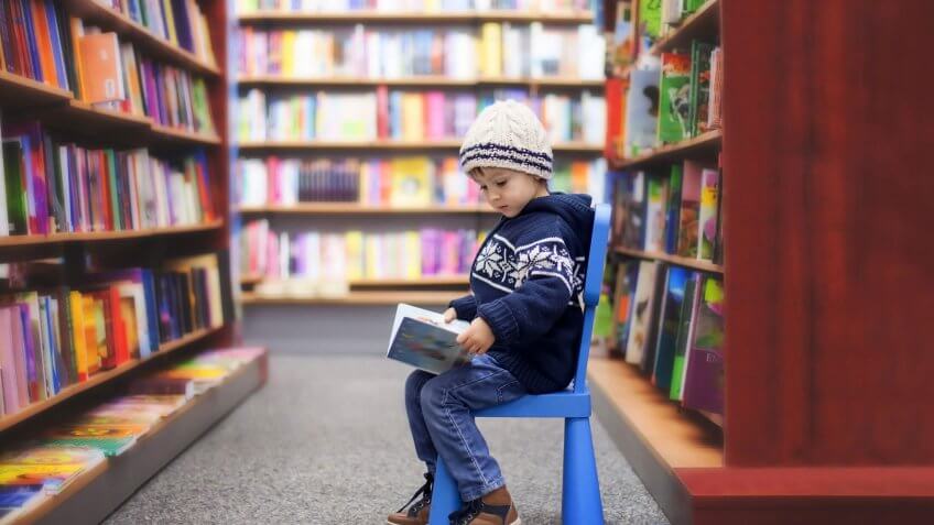 child sitting in a library reading a book