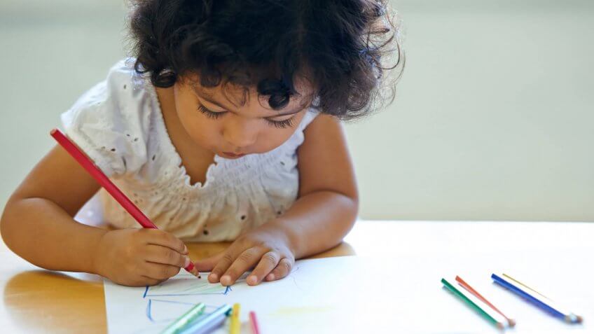 young girl drawing with colored pencils
