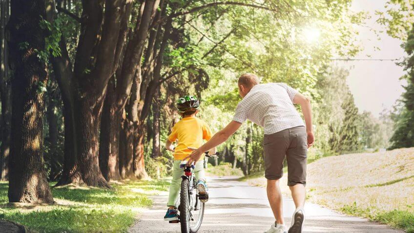man teaching a child how to ride a bike