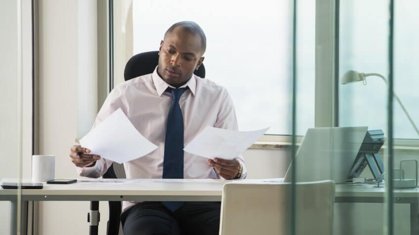 1 Person, 25-29 years, Adults Only, Business, Businessman, Businesswear, CEO, Concentration, Corporate, Desk, Document, Electric Lamp, Entrepreneur, Entrepreneurship, Examining, Executive, Male, Manager, Necktie, Nigerian, Office, One Man, Other Keywords, Shaved Head, Things to Know About High-Yield CDs, Transparent, Window, Work Environment, Working, Young Adult, Young Adult Man, african, african ethnicity, black, business attire, businessperson, coffee cup, communication, front view, glass, holding, indoor, indoors, laptop, mug, paperwork, professional, reading, shirt and tie, sitting, workplace, young man