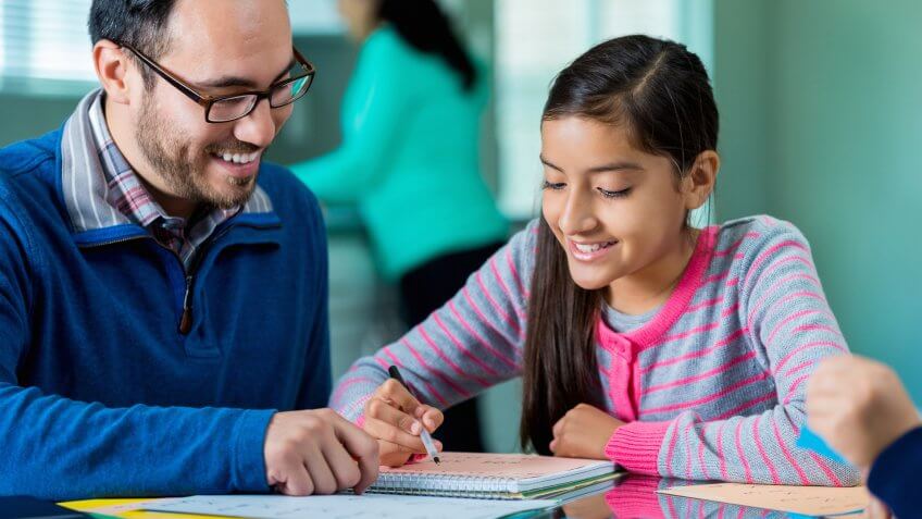 Pre-teen girl works on homework assignment at kitchen table.