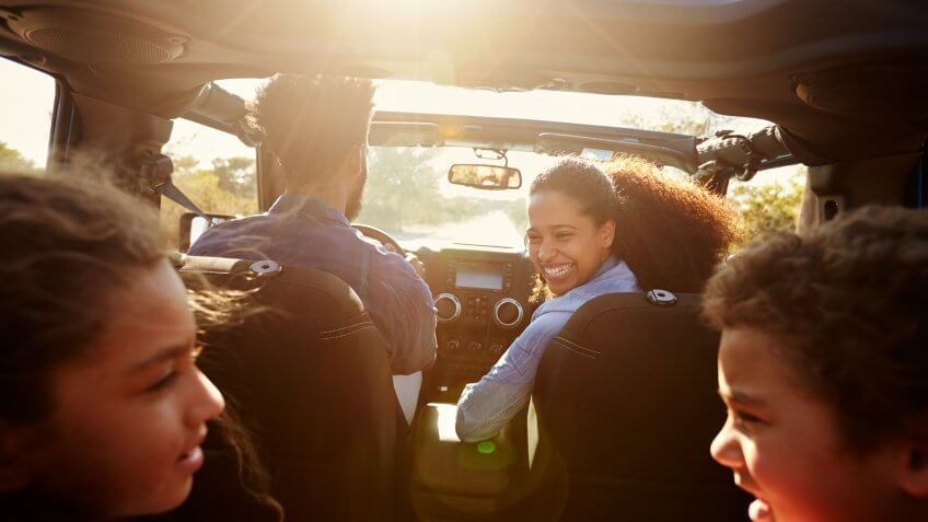 Happy family on a road trip in their car, rear passenger POV.