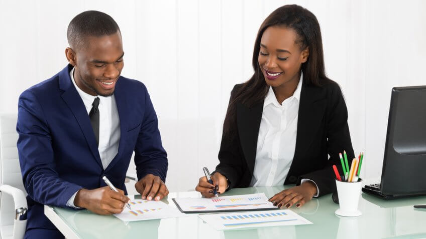 Financial advisor and client pointing to stock charts with pens