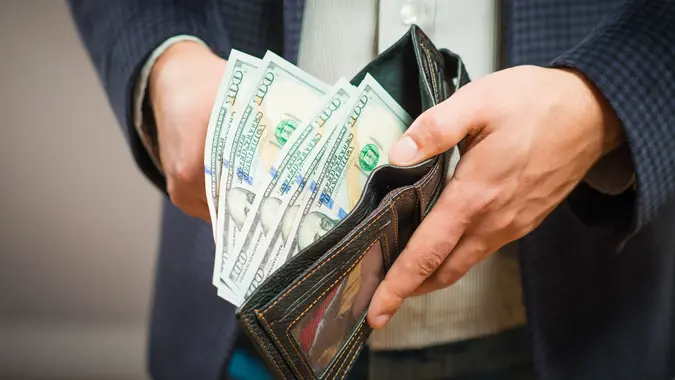man fanning $100 out of a wallet