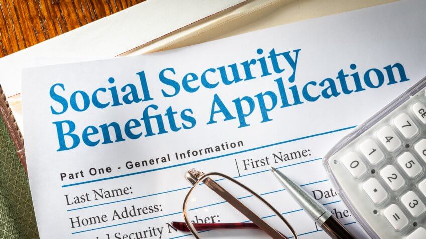Social Security Benefits form with pen, glasses, and calculator.