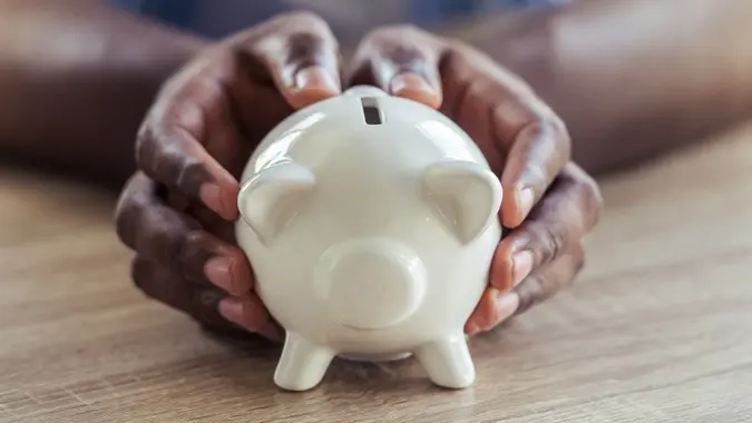 Cropped image of handsome Afro American businessman holding a piggy bank.