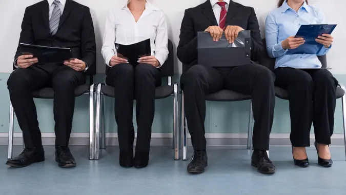 Close-up Of Businesspeople With Files Sitting On Chair.
