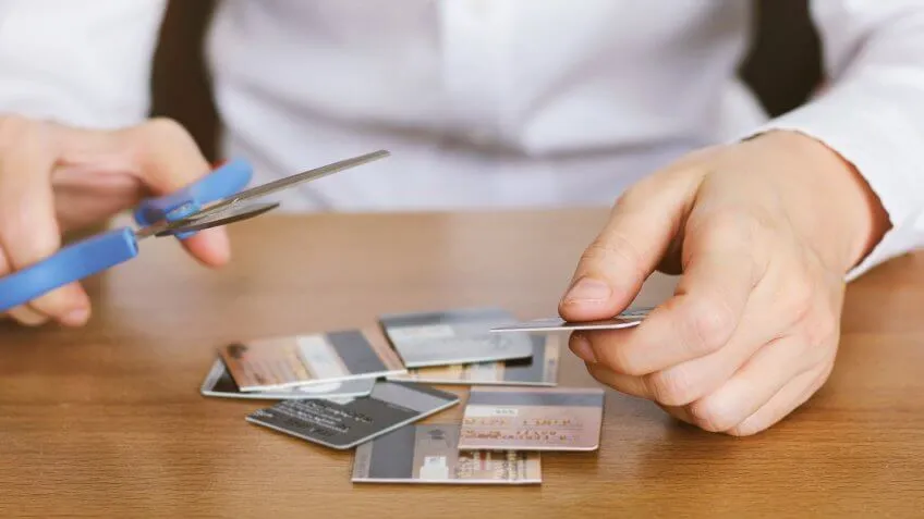 Person cutting credit cards using scissors