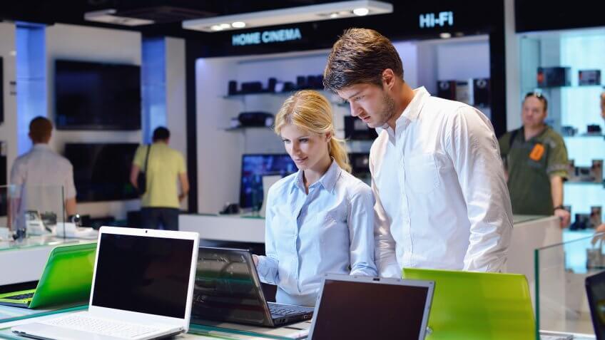 people looking at laptops in store