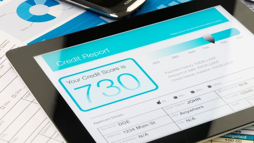 Credit report on a digital tablet with paperwork.