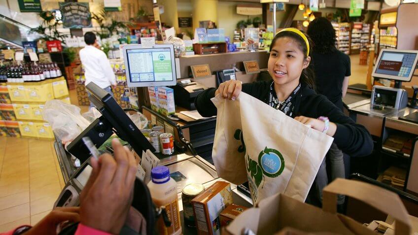 PASADENA, CA - APRIL 22: Cashier Michelle Yulo hands out free reusable grocery bags at a Whole Foods Market natural and organic foods stores which is ending the use of disposable plastic grocery bags in its 270 stores in the US Canada and UK on Earth Day, April 22, 2008 in Pasadena California.
