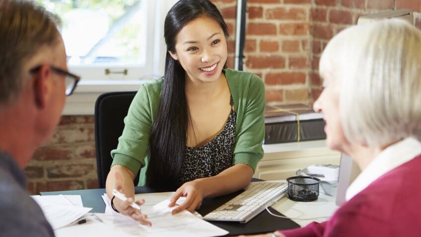 Conduct thorough research to find a financial advisor. young woman speaking to older couple in office