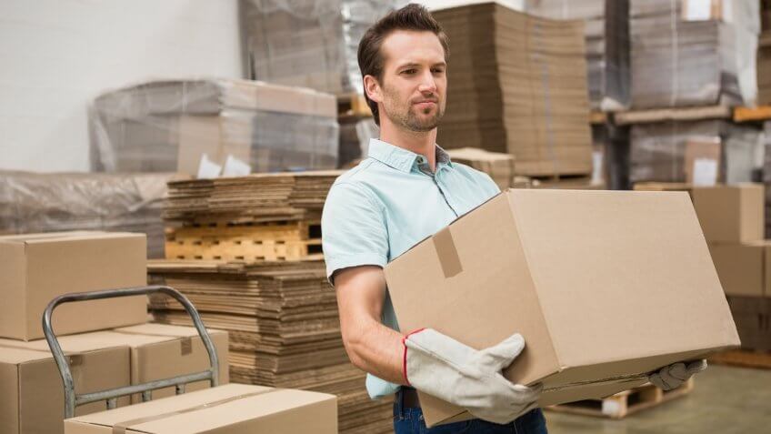man carrying cardboard box in warehouse