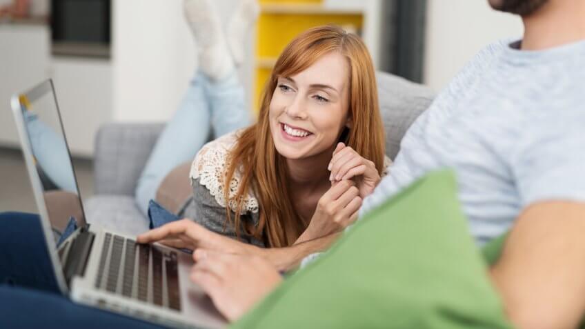 woman on couch looking at man's computer