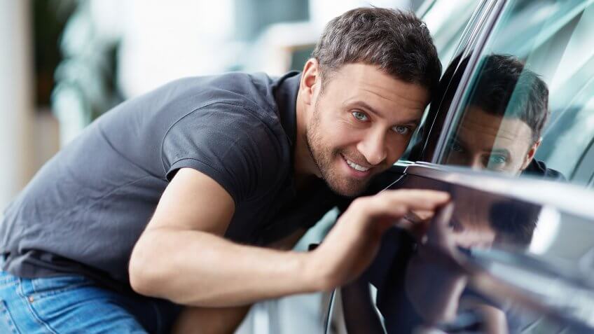 man inspecting side of car
